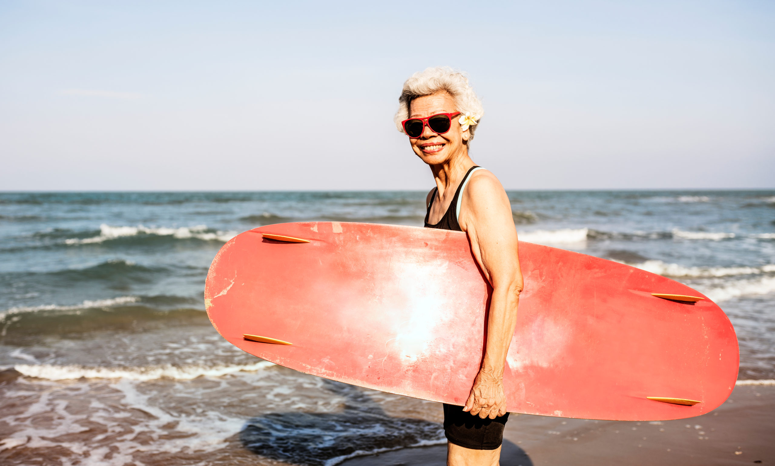 elder sufer lady with a board before entering the sea