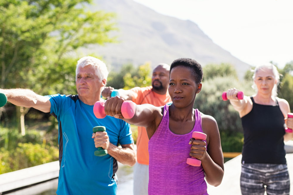 Happy seniors and mature couples exercising with dumbbells. Healthy multiethnic people exercising using dumbbells outdoor.